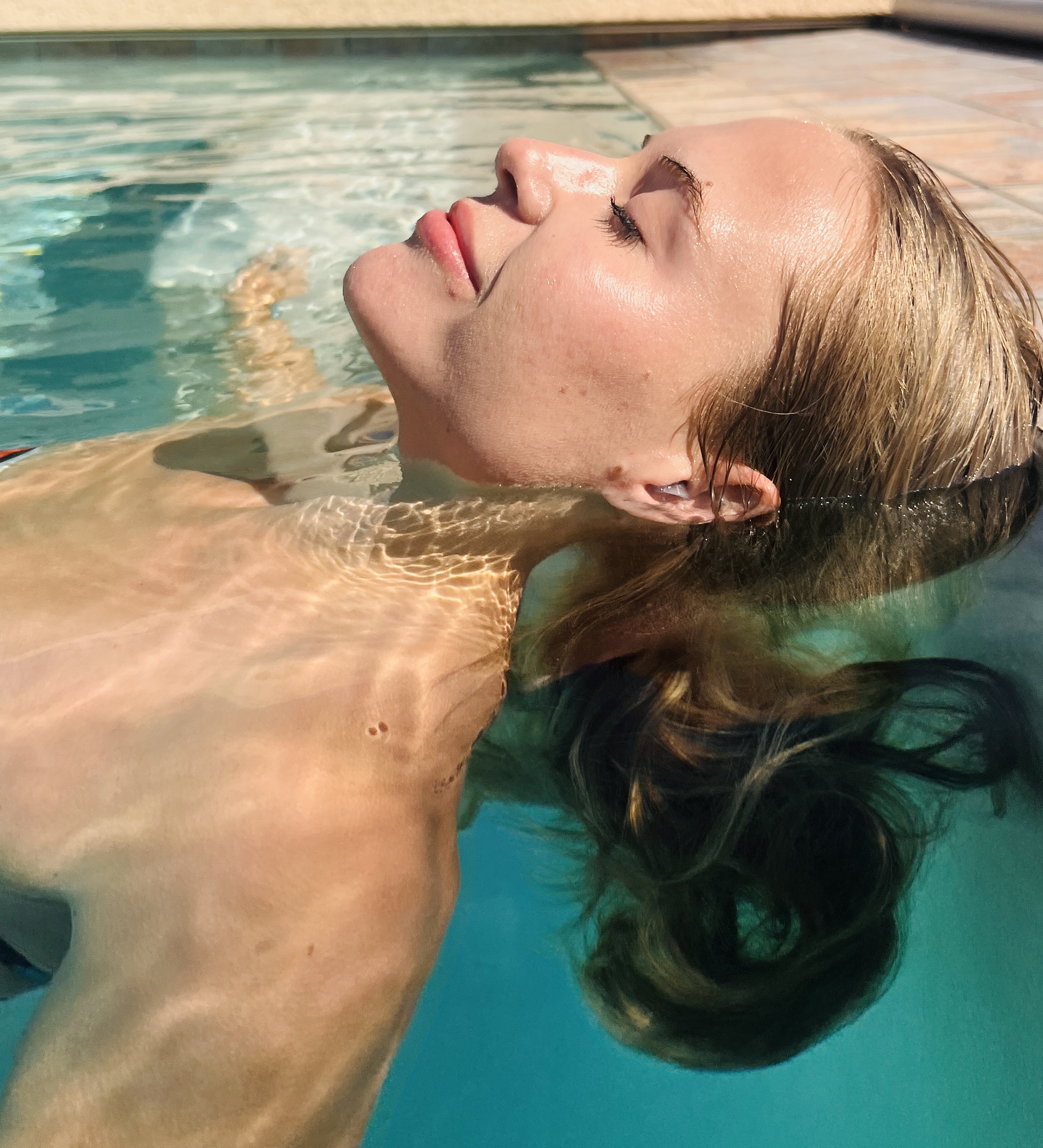 Frau ruht sich im Schwimmbecken mit eingesetzten Watersafe-Ohrstöpseln aus